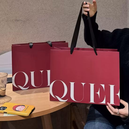 高級カスタムロゴプリント紙ギフトショッピングバッグ、ハンドルとリベット付きクラフト衣料品ショッピングバッグ、化粧品や衣類を運ぶための紙袋